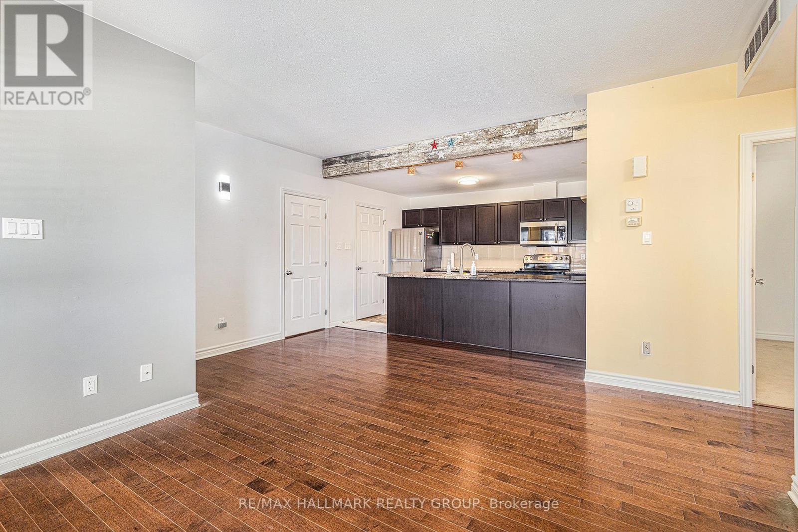 A spacious kitchen with dark wood floors and white walls.