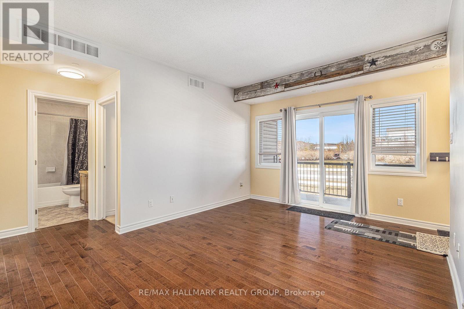 A spacious room with wooden flooring and a view of the outside through the windows.