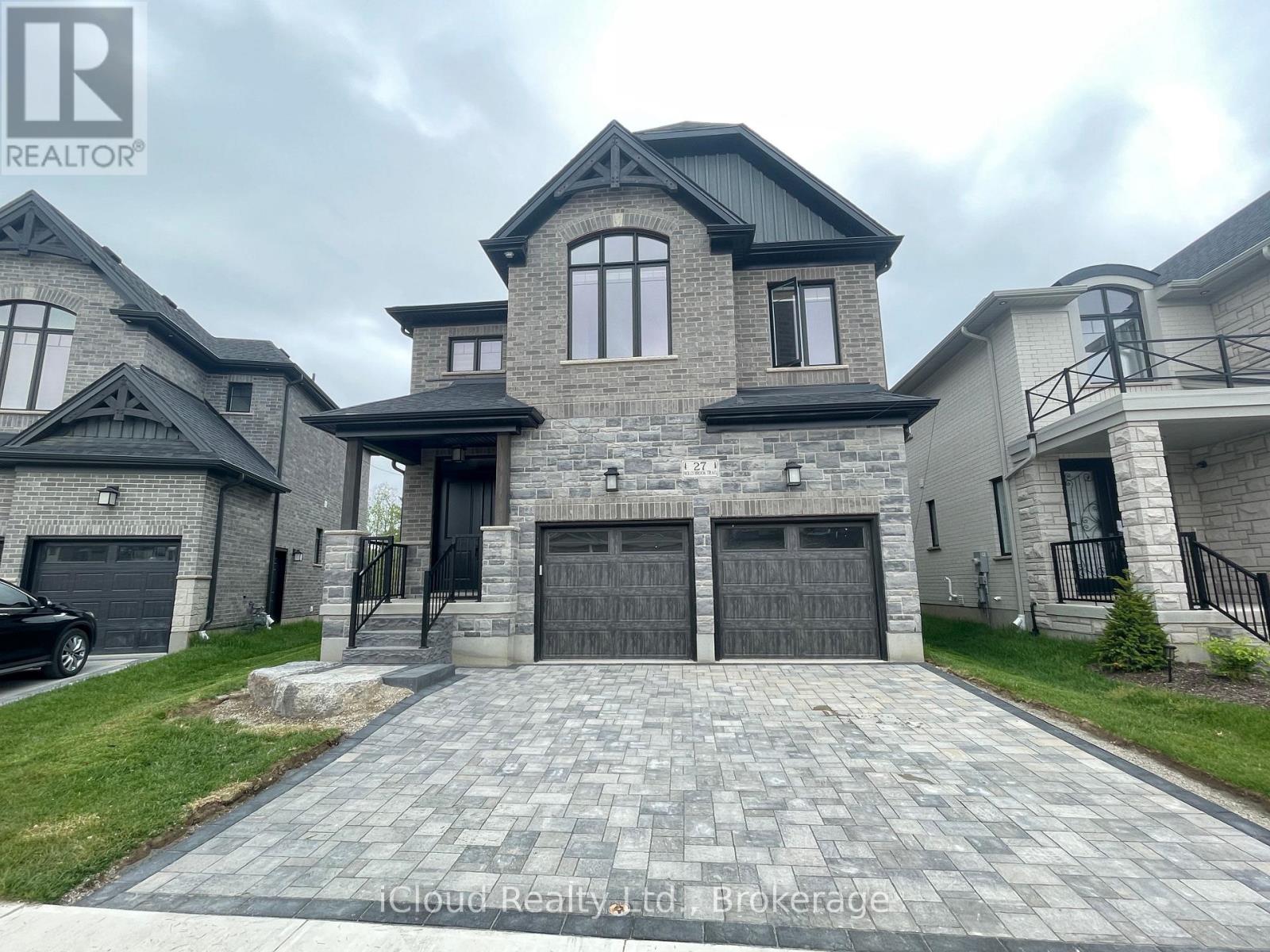 A large house with a grey front yard and a black car parked in the driveway.