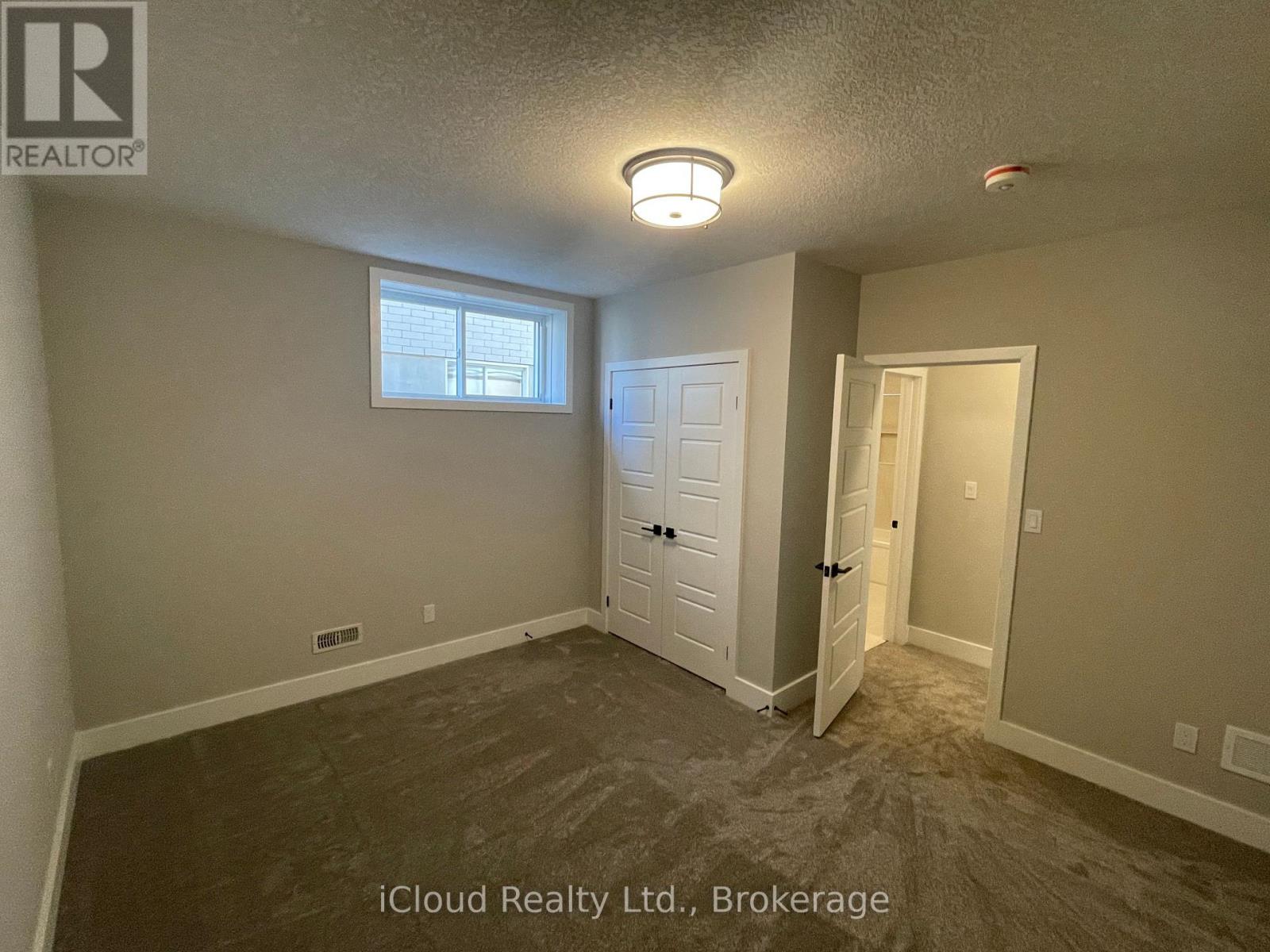 A room with a window, a door, and a ceiling light.