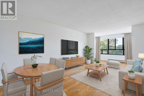 A living room with a wooden table and chairs, a television, and a painting on the wall.
