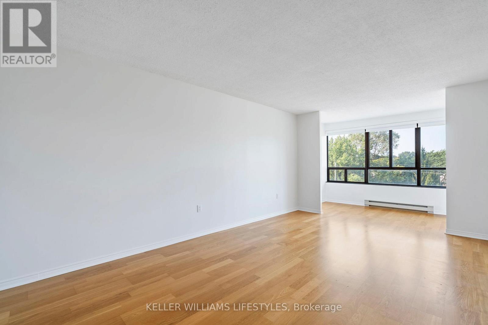 A spacious room with wooden flooring and a large window.