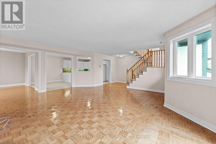 A spacious room with a wooden floor and a staircase.