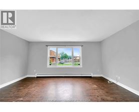 A room with a large window and wooden flooring.