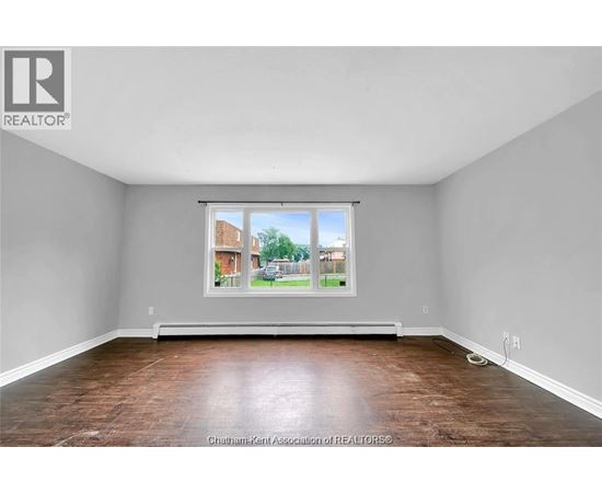 A room with a large window and wooden flooring.