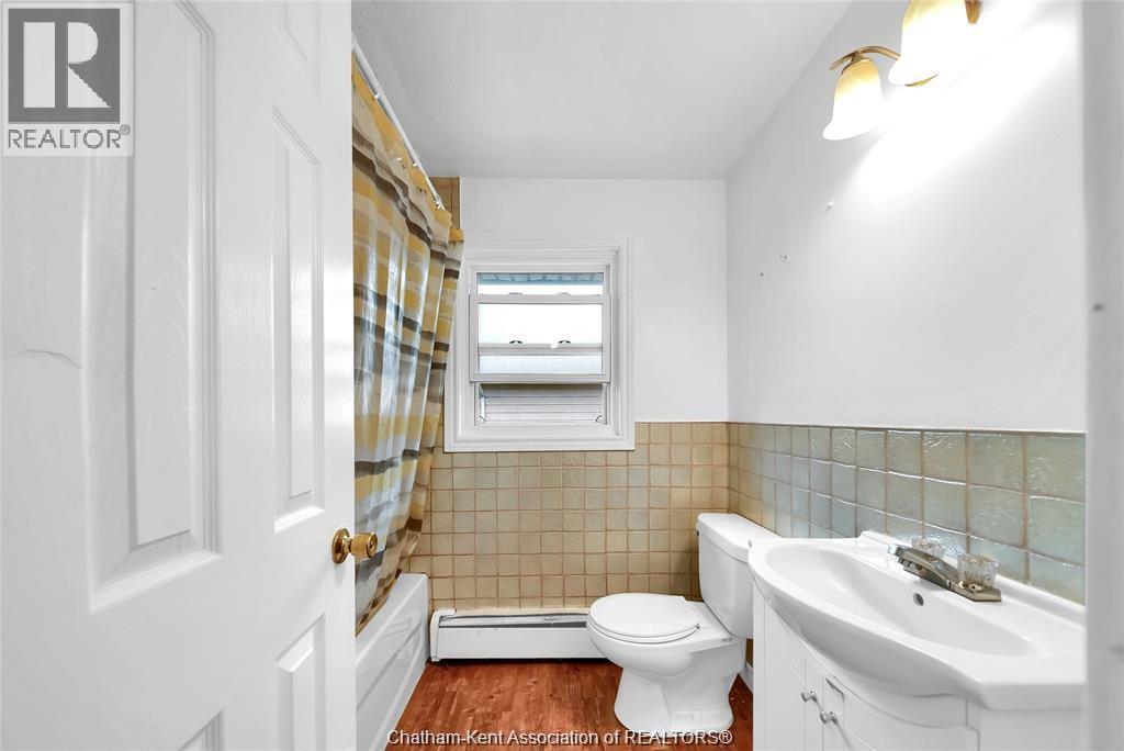 A white bathroom with a toilet, sink, and a window.