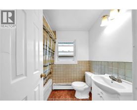 A white bathroom with a toilet, sink, and a window.