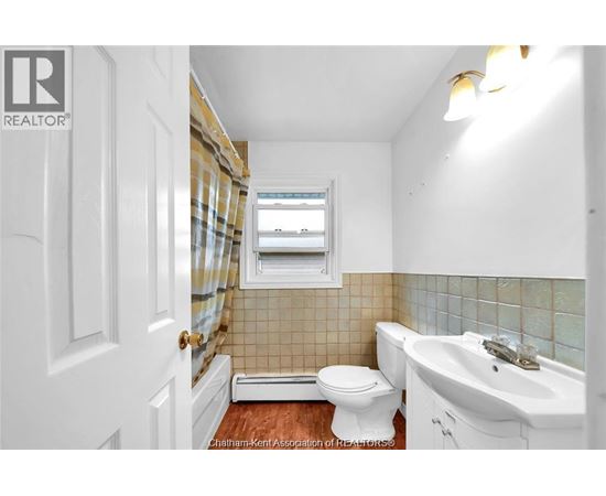 A white bathroom with a toilet, sink, and a window.
