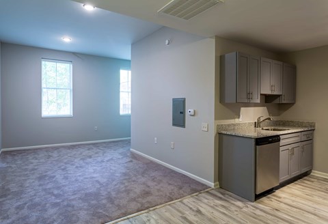 A kitchen area with a sink, cabinets, and a window.