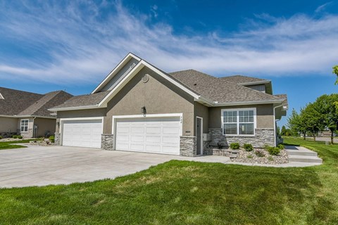 A house with a grey roof and two white garage doors.
