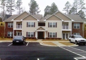Apartment building with a parking lot in front.
