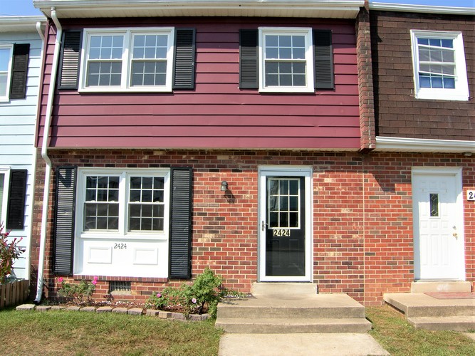 A red brick house with a black door and a white door.