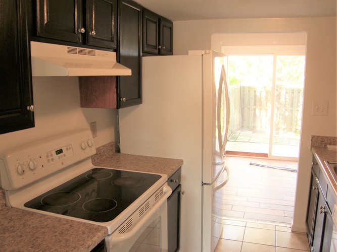 A kitchen with black cabinets and a white stove top oven.