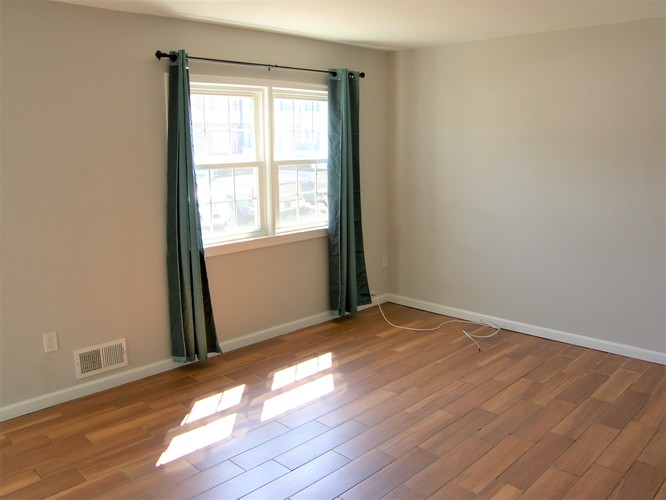 A room with a window and a wooden floor.