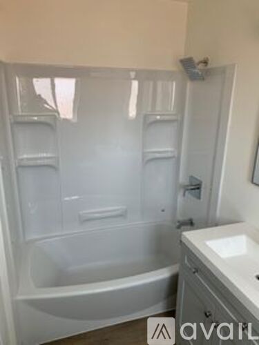 A white bathroom with a bathtub, sink, and towel rack.