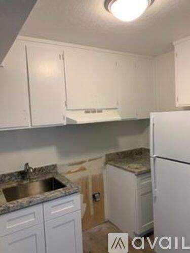 A kitchen with white cabinets and a granite countertop.