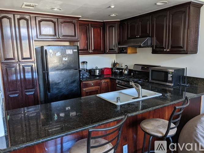 A kitchen with dark wood cabinets and black appliances.