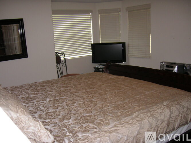 A bedroom with a bed, a television, and a fan.