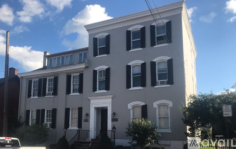 A white building with black shutters and a sign that says "For Sale".