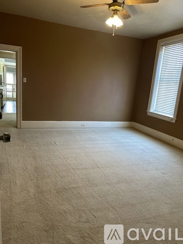 A room with a carpeted floor and a ceiling fan.