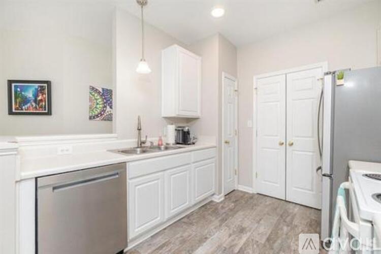 A kitchen with white cabinets and a stainless steel refrigerator.