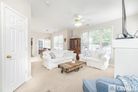 A living room with white furniture and a flat screen TV.