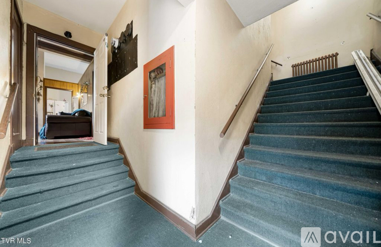 A staircase with a blue carpeted runner and wooden handrails.