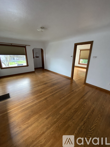 A room with wooden floors and a window with blinds.