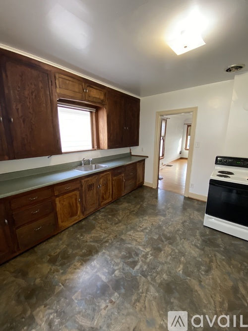 A kitchen with wooden cabinets and a marble floor.