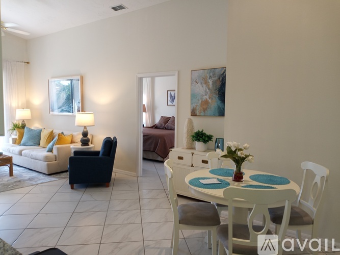 A living room with a white couch, a brown sofa, a white table with a vase of flowers, and a painting on the wall.