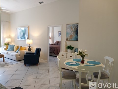 A living room with a white couch, a brown sofa, a white table with a vase of flowers, and a painting on the wall.