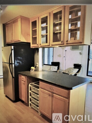 A kitchen with wooden cabinets and a black refrigerator.