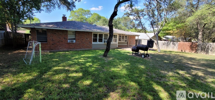 A backyard with a house, a tree, and a swing set.
