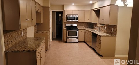 A kitchen with brown cabinets and a granite counter top.