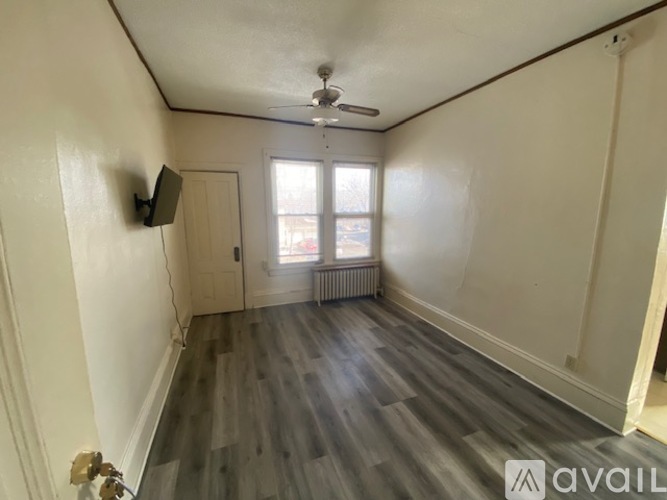 A room with a carpeted floor, a window with blinds, and a radiator.