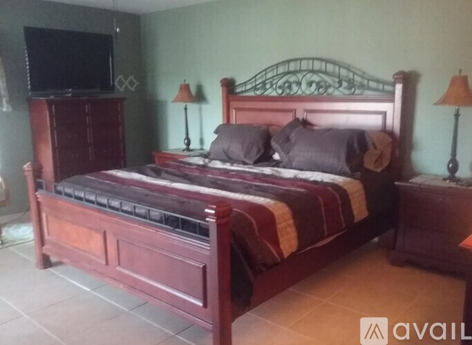 A bedroom with a large bed and a television on the dresser.