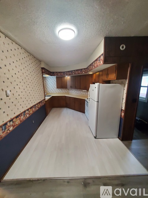 A bedroom with a bed, a refrigerator, and a wall with a patterned border.