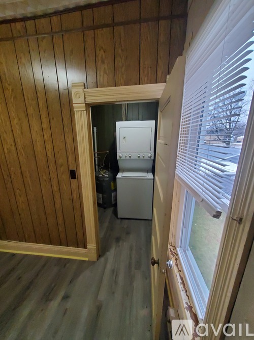 A small room with a window and a door leading to a kitchen.