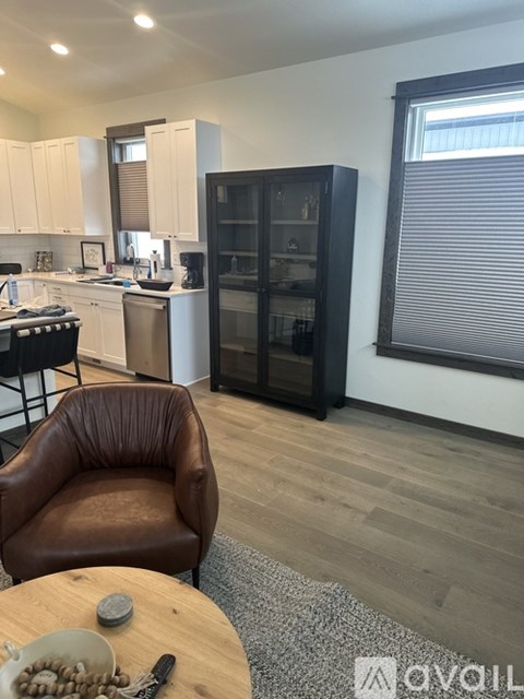 A kitchen with a brown leather chair and a wooden table with a bowl on it.