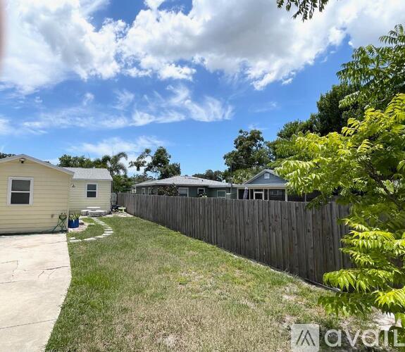 A backyard with a wooden fence and a house in the background.