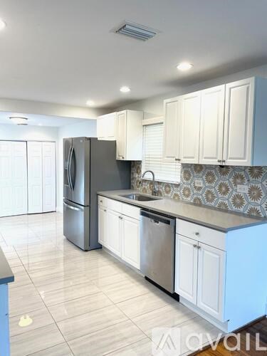 A kitchen with white cabinets and a patterned backsplash.