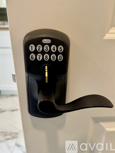 A black keypad with numbers 1 to 0 is mounted on a white wall.