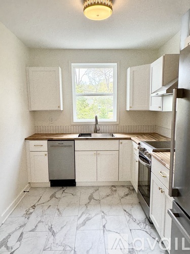 A kitchen with white cabinets and marble flooring.
