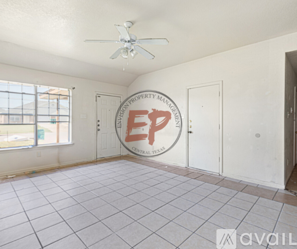 Empty room with a ceiling fan and a logo on the wall.