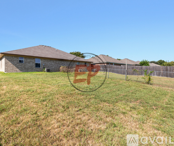 A house with a fence and a grassy field in front of it.