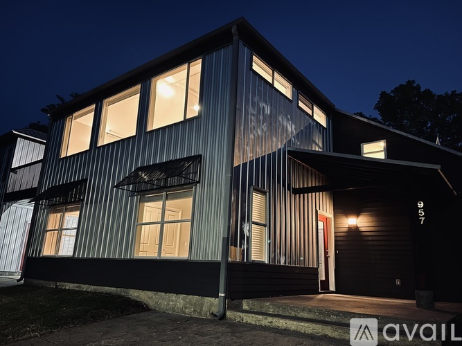 A modern house with a dark facade and lit windows at night.