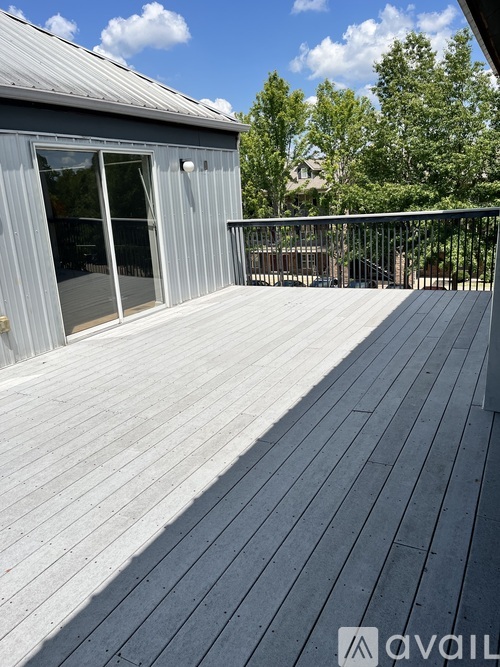 A wooden deck with a metal railing and a grey building in the background.