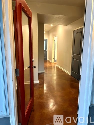 A hallway with a brown floor and white walls.