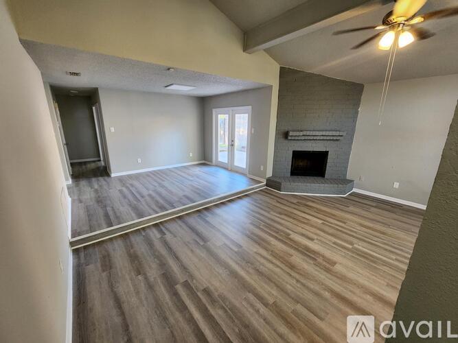 A spacious living room with wood flooring and a fireplace.