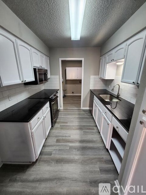 A kitchen with white cabinets and black countertops.